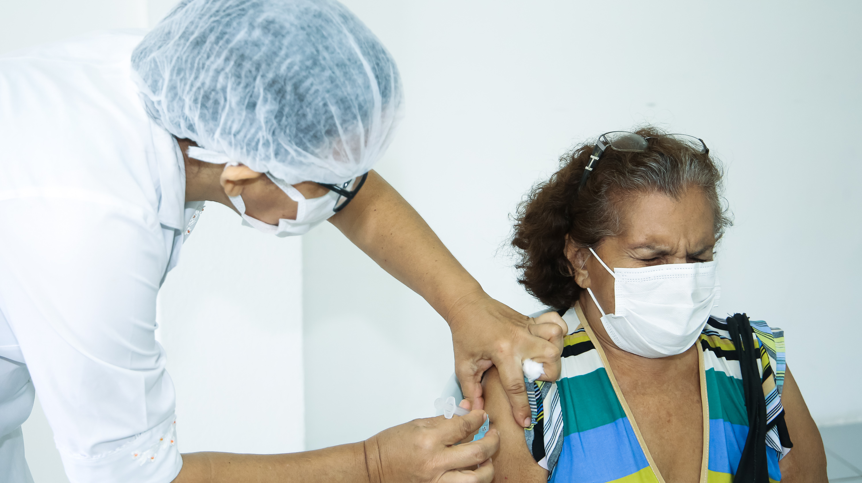 senhora de máscara sendo vacinada